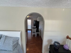 A narrow hallway leading to a dining area with a table and chairs, a kitchen with cabinets, and a bed with a patterned blanket. - Retro Retreat! 2BR, 1 Bath Home with WiFi, AC in wonderful Bristol, VA (Bristol)