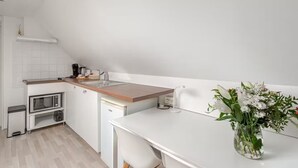 A modern kitchen with white cabinetry, a wooden countertop, a built-in microwave, and a small sink. There is a vase with flowers on the countertop. - Under a perched roof, a small cocooning studio with private Spa (Grez-Doiceau)