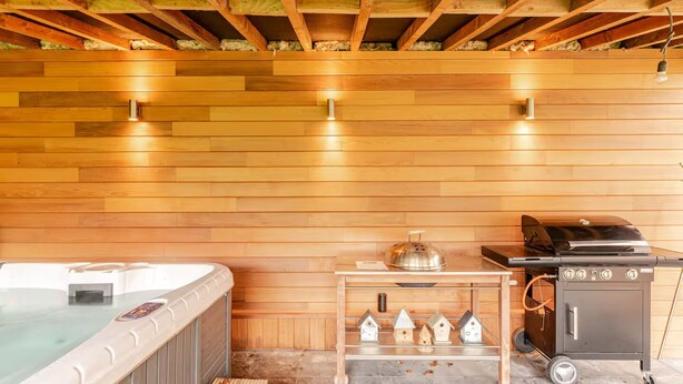 A wooden interior with a hot tub, a grill, and a small table with birdhouses. - Under a perched roof, a small cocooning studio with private Spa (Grez-Doiceau)