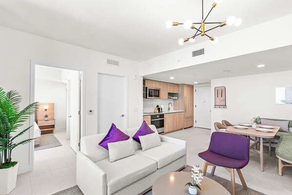 A modern living room with a sofa, a coffee table, and a dining area with a table and chairs.