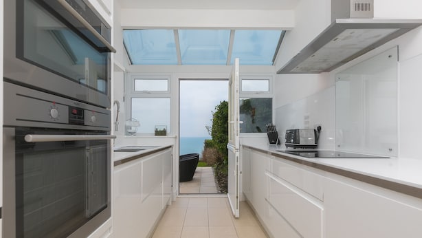 A modern kitchen with a built-in oven, a coffee machine, and a view of the outdoors. - Heatherleigh, Carbis Bay – Sleeps 8 – Sea Views – Dog-Friendly - On-Site Parking (Carbis Bay)