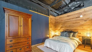 Une chambre à coucher avec une armoire en bois, un lit avec une literie blanche et une table de chevet avec une lampe.