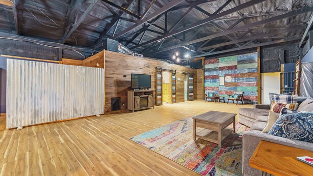 Un vaste espace de vie doté d’un plancher en bois, d’un tapis coloré, d’un canapé, d’une table basse et d’un téléviseur.