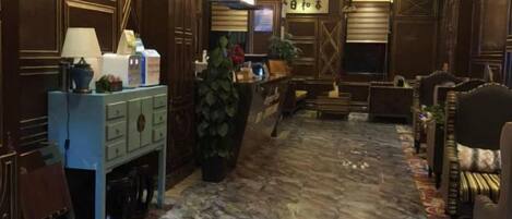 A lobby with a reception desk, seating area, and a chandelier.