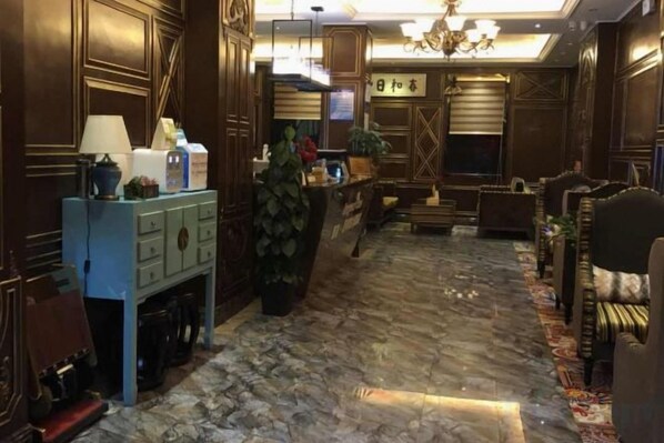 A lobby with a reception desk, seating area, and a chandelier.