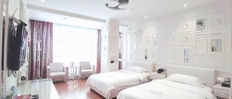 A hotel room with two beds, a desk, a chair, and a television.