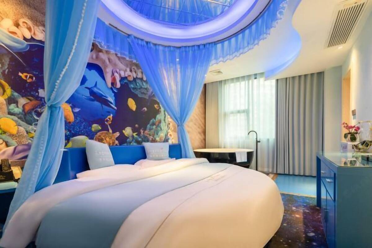 A bedroom with a large bed, a mural of marine life, and a canopy.