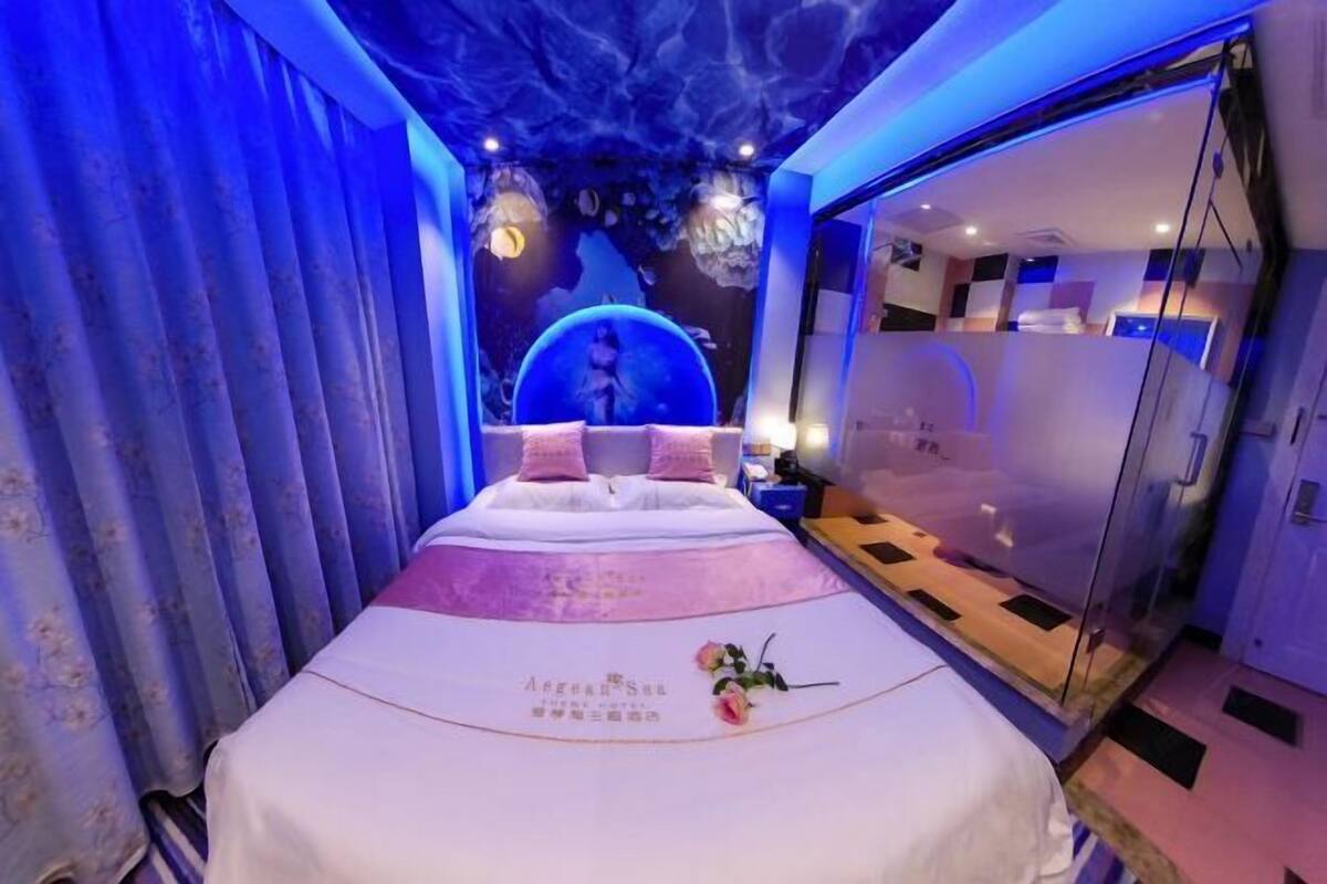 A bedroom with a bed, a glass partition, and a wall with a circular design.