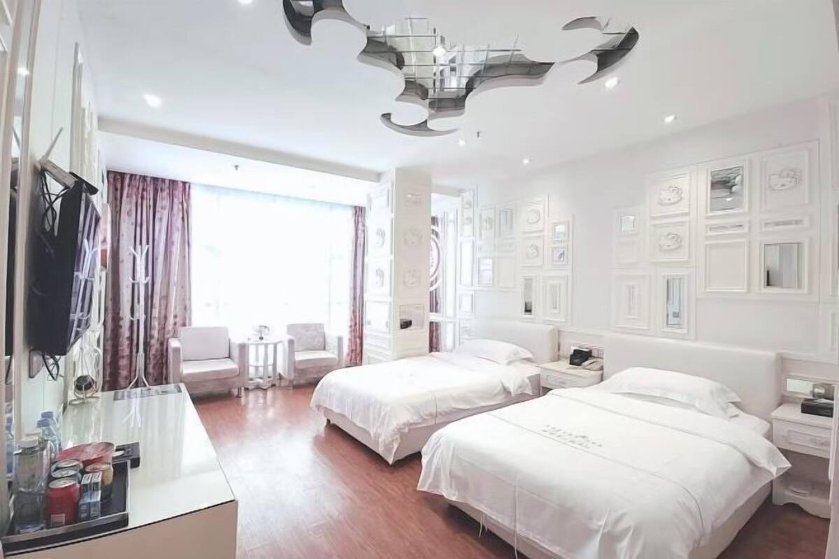 A hotel room with two beds, a desk, a chair, a small table, and a decorative wall panel.