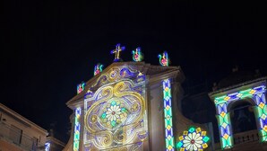 Un bâtiment dont la façade présente des motifs lumineux complexes, avec un clocher et une grande entrée.
