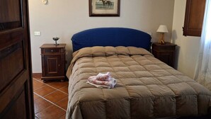 A bedroom with a bed, a nightstand, a lamp, a framed picture on the wall, and a door. - Relaxation, sea, nature, culture! (Sicilia)
