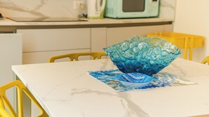 Une cuisine avec un plan de travail blanc, un saladier en verre bleu et un four à micro-ondes.