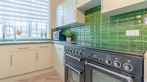 Une cuisine équipée d’une cuisinière, d’un four et d’un plan de travail recouvert de carreaux verts.