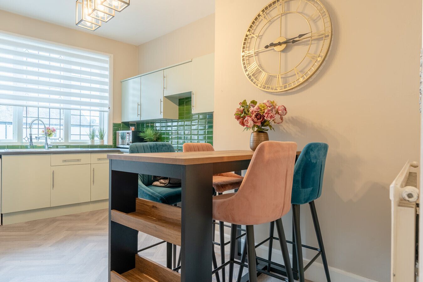 A modern kitchen with a wooden table, two chairs, and a large wall clock.