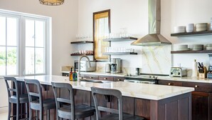 A modern kitchen with a large island, bar stools, a built-in oven, and a coffee maker. - Casa Playa Denver &Mistico Beach Club+Boat Shuttle (San Pedro)