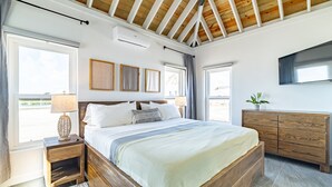 Et soveværelse med en træseng, sengeborde, en kommode og et fjernsyn.