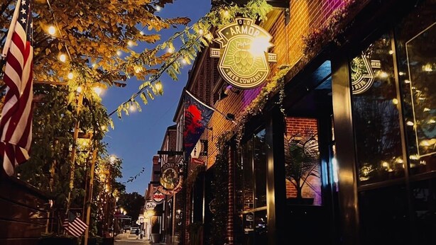 A street lined with brick buildings, some with illuminated signs, and an American flag. - NEW-Heart of Kannapolis-Modern & Charming Escape (Kannapolis)