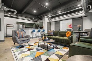 A modern living room with a sofa, armchairs, a coffee table, and a kitchen area in the background. - Historic Newark Station- 10% off Earthworks Cafe (Newark)