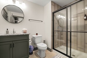 A modern bathroom with a glass shower enclosure, a toilet, and a vanity with a mirror and countertop. - Historic Newark Station- 10% off Earthworks Cafe (Newark)