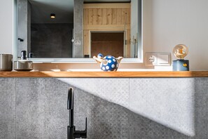 A modern kitchen with a wooden countertop, a large window, and a decorative blue pot with white polka dots.