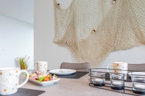 Een eettafel gedekt met een bord eten, twee gemasterde mokken en een kandelaar.