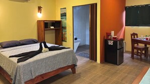 Una habitación de hotel con cama, kitchenette pequeño, zona de comedor y baño.