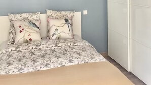 Ein Schlafzimmer mit einem Bett, zwei Kissen, einer Pendelleuchte und einem Kleiderschrank.