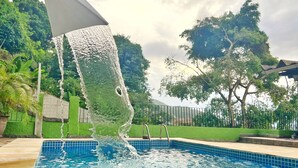 Una piscina con agua azul cristalina, rodeada de césped verde y árboles.