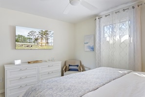 A bedroom with a bed, a dresser, a chair, and two framed pictures on the wall.