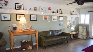 Un salon avec un canapé en cuir vert, une table en bois et un ventilateur de plafond.