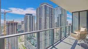 Un balcón con vistas a edificios altos, una grúa de construcción y una zona de piscina.