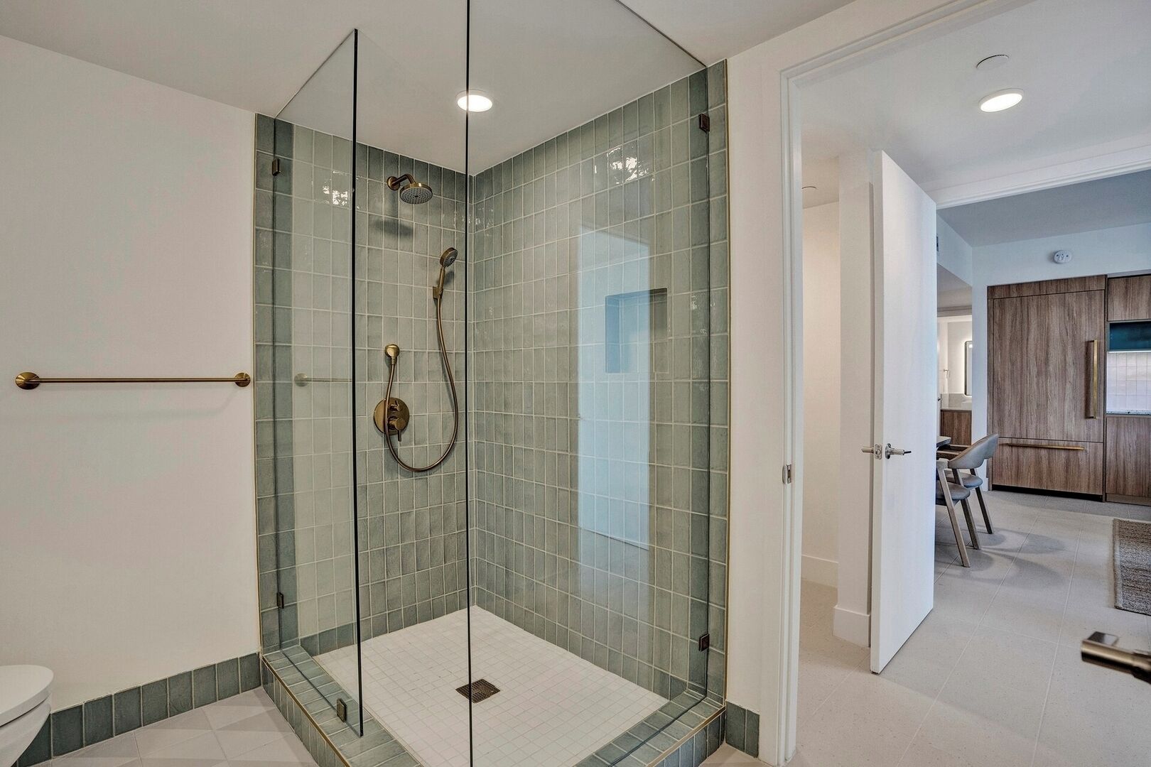 A modern bathroom with a glass-enclosed shower, tiled walls, and a visible toilet.