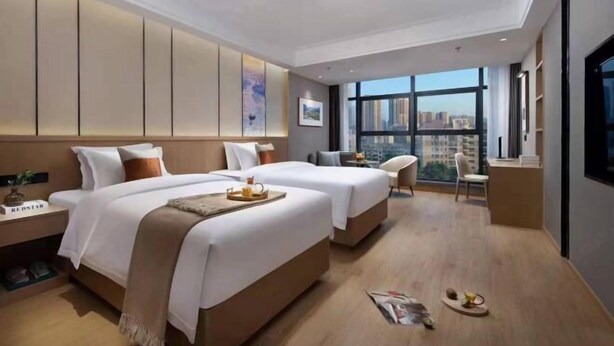 A modern hotel room with two beds, a desk, and a large window offering a city view. - Fu Quan Hotel (Wuchuan Haibin Bus Terminal) (Wuchuan)