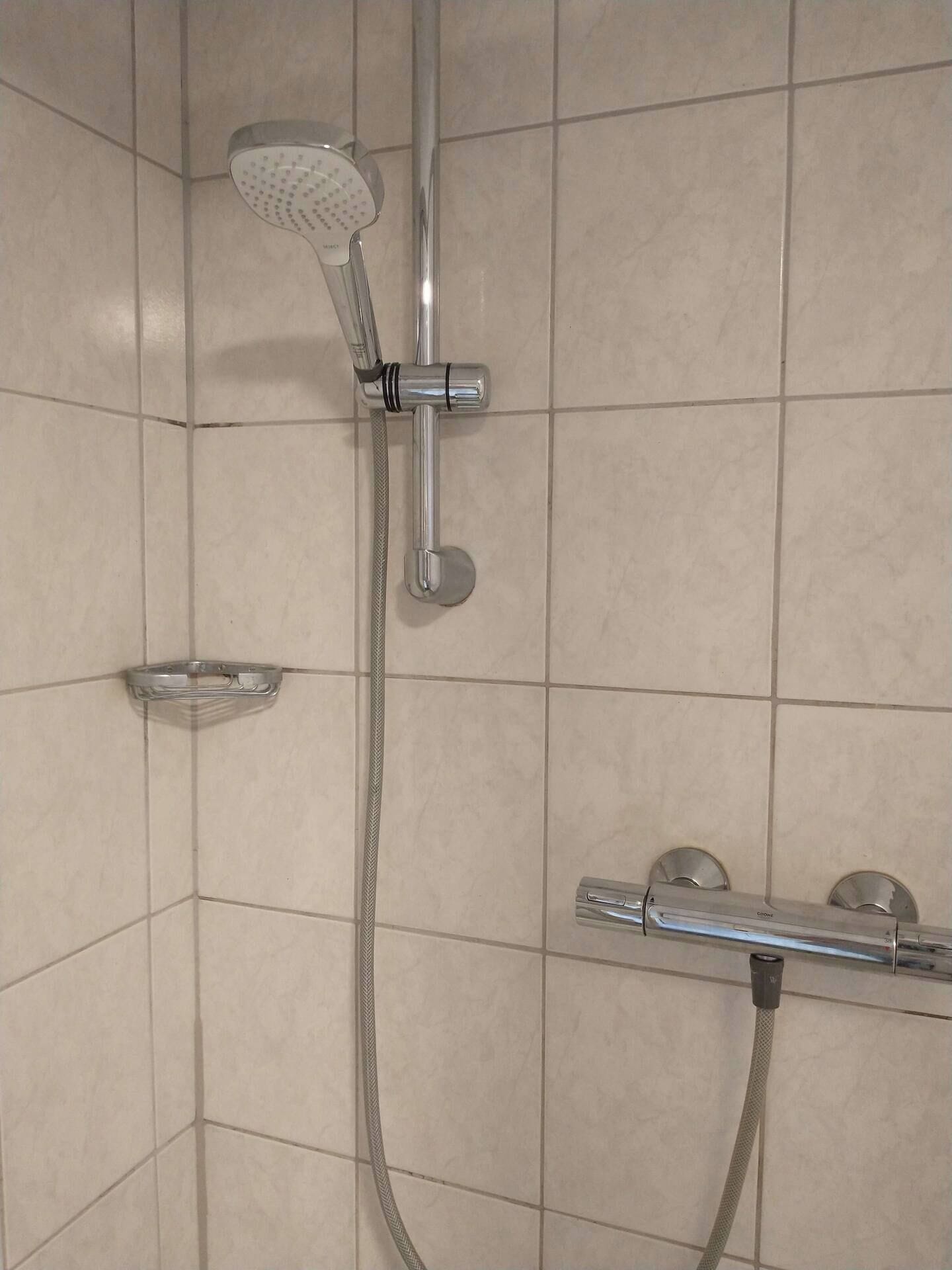 A shower with a handheld showerhead and a handheld hose.