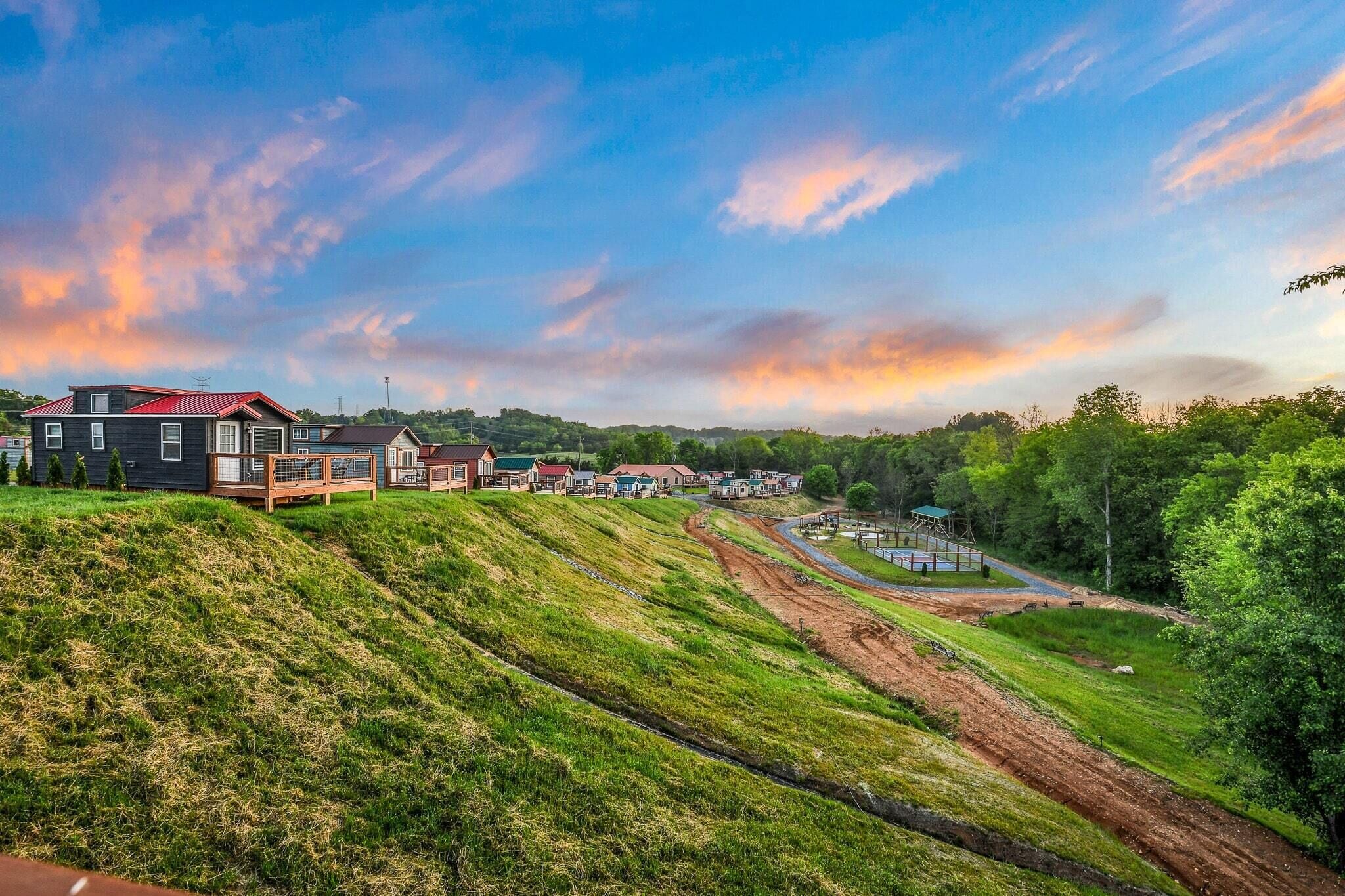 Un quartier résidentiel avec des maisons construites sur une colline, un chemin de terre et un petit pont.