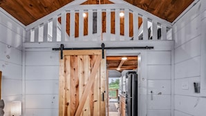 A wooden interior with a large sliding barn door leading to a kitchen area.