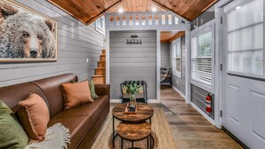 A cozy interior with a wooden ceiling, a brown leather sofa, a small round table, and a fire extinguisher on the wall.