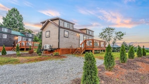 A two-story house with a wooden deck, a covered outdoor area, and a gravel driveway.