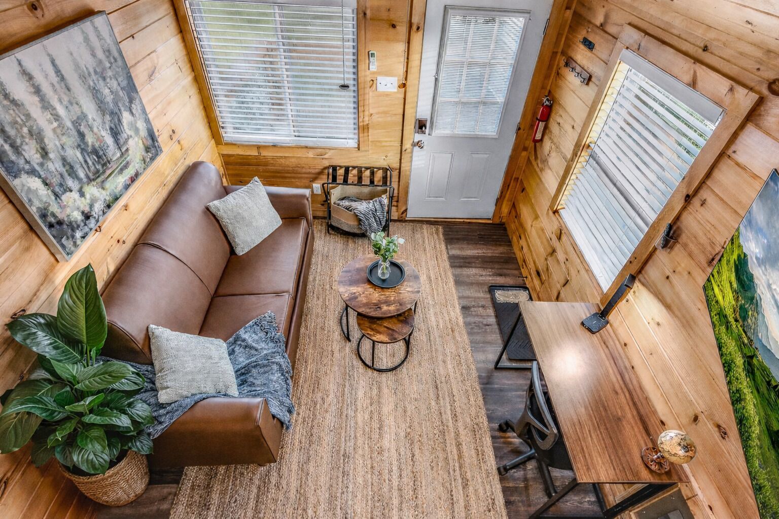 A cozy cabin interior with a sofa, a round coffee table, and a dining table.