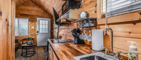 L’intérieur d’un chalet en bois chaleureux et accueillant comprend une cuisine avec un plan de travail en bois, un évier et un coin repas avec une table et des chaises.