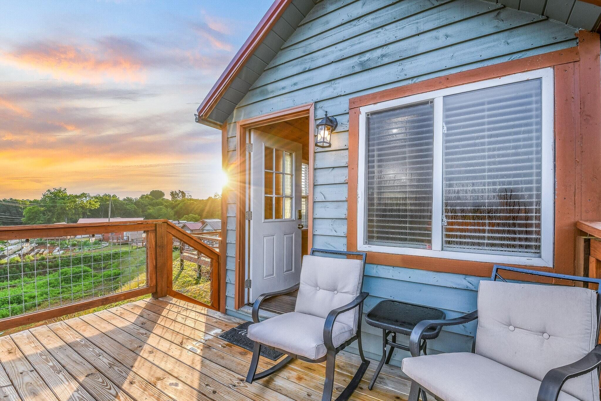 A wooden deck with two chairs and a table, overlooking a green landscape.