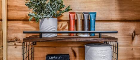 A wooden shelf with makeup products, a potted plant, and a tissue roll.