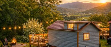 A small cabin with a fire pit, outdoor seating, and string lights.
