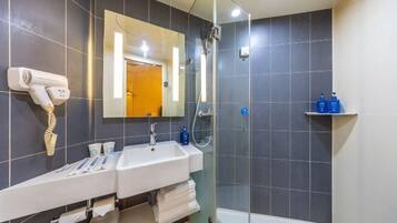 Une salle de bain moderne équipée de deux lavabos, d’un sèche-cheveux, d’un miroir et d’une cabine de douche.
