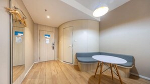 A modern room with a wooden floor, a round table with a white top, a blue bench, and a curved wall. - Meiwu Hotel (Lanzhou Dngfanghong Square Railway Bureau Store) (Lanzhou)