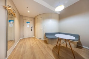 Une pièce moderne avec un plancher en bois, une table ronde au plateau blanc, un banc bleu et un mur incurvé.