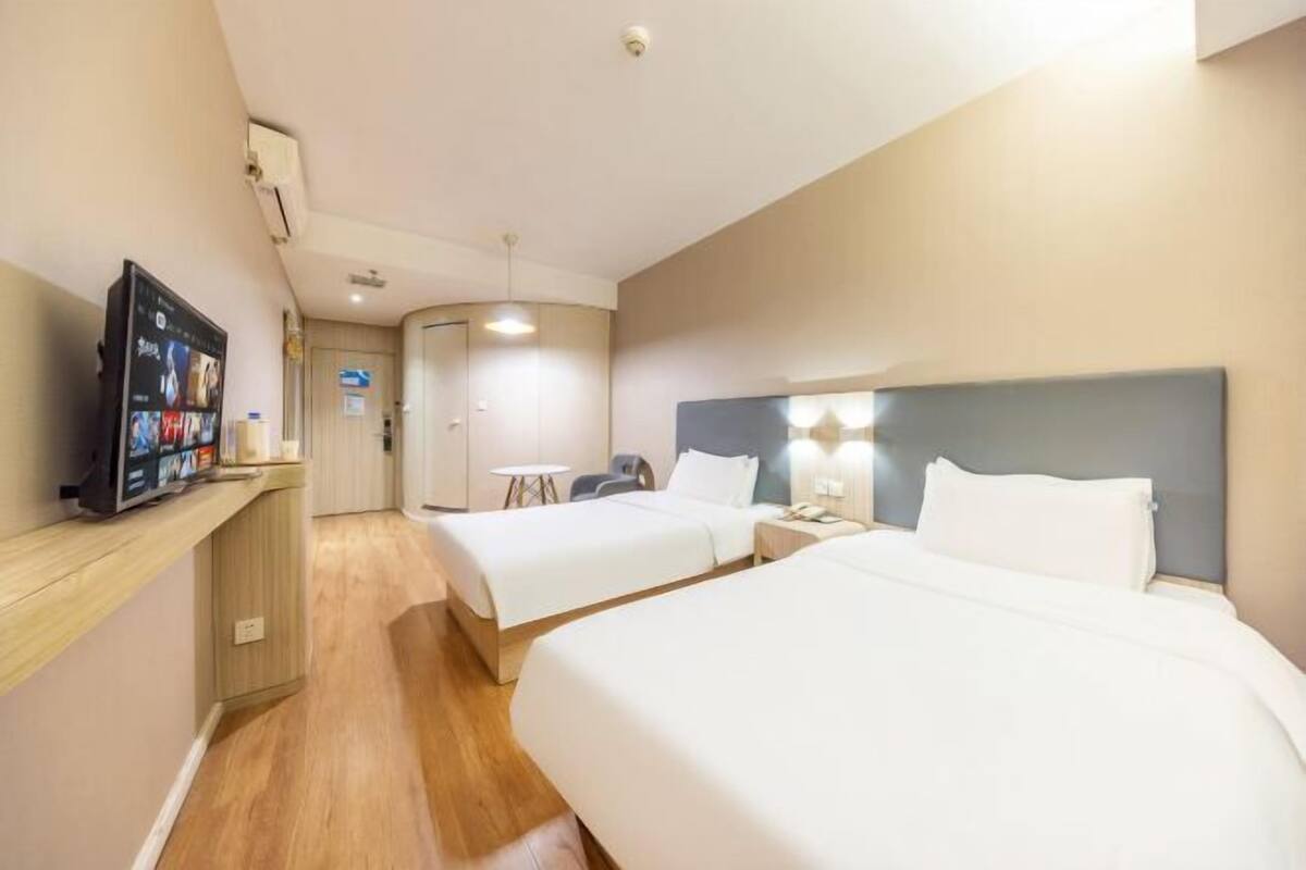 Una habitación de hotel con dos camas, televisión, escritorio y una mesita.