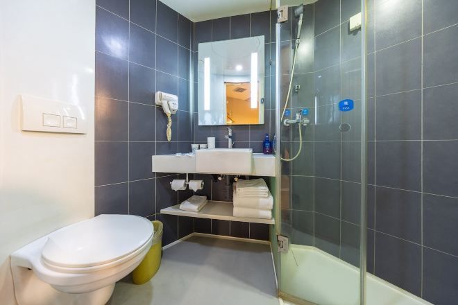 Une salle de bain équipée de toilettes, d’un lavabo, d’un miroir et d’une douche.