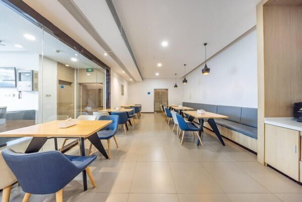 A modern dining area with tables and chairs, a bench, and a counter. - Meiwu Hotel (Lanzhou Dngfanghong Square Railway Bureau Store) (Lanzhou)