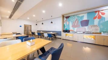 Un espace repas moderne avec des tables et des chaises, un comptoir de cuisine et une fresque colorée sur le mur.